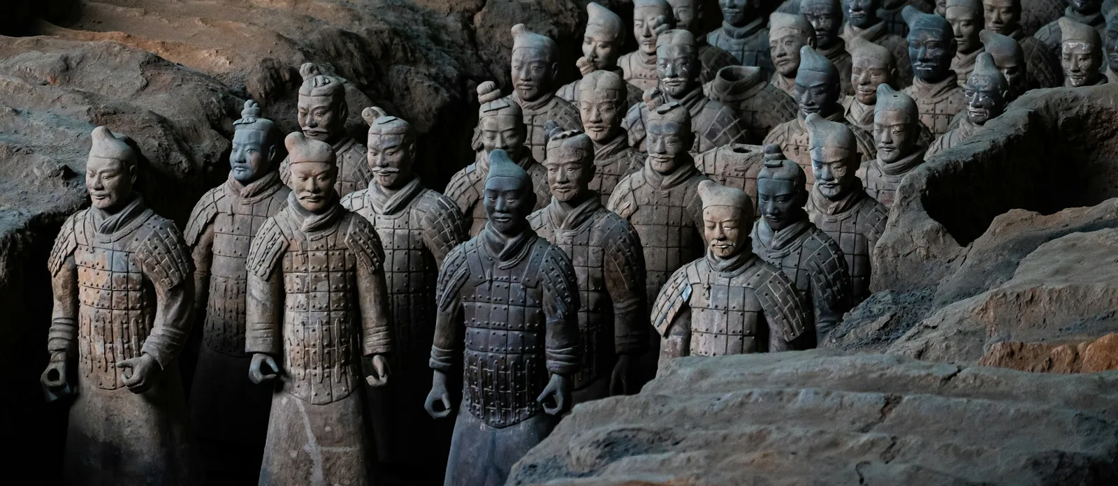 Terracotta warrior figures standing in rows inside an excavation hall